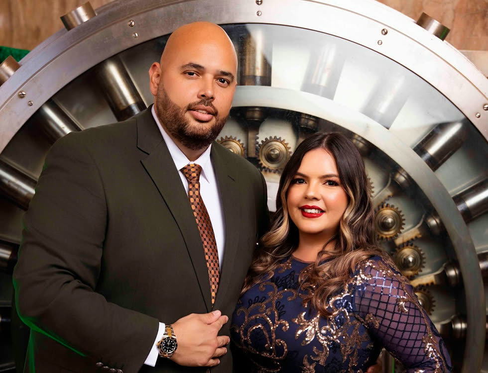 Ruddy Rodríguez and Nicolás Bordones, founders of Gold Star Insurance, standing in front of a bank vault door